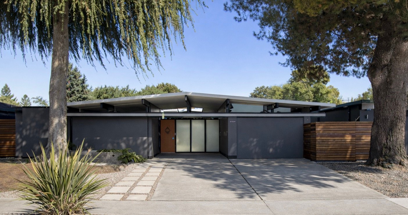 A San Jose Eichler with wide overhanging eaves, a glass gable, and mature trees